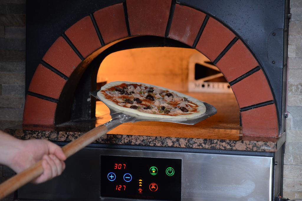 Symphony Style Hotel Kuwait Salmiya Kültér fotó Pizza being removed from a wood-fired oven